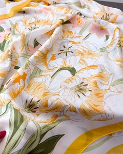 Detailed view of floral silk scarf featuring yellow tulips and vibrant green leaves