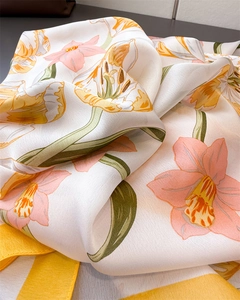 Detailed close-up of floral print silk scarf with lilies and bright yellow border