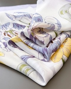 Close-up of pearl white silk scarf with vibrant lily flower patterns and soft texture