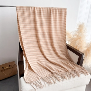 Detail of classic houndstooth scarf with elegant fringes on a minimalist chair