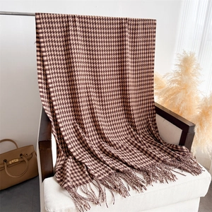 Detail of classic houndstooth scarf with soft fringe edges in brown and beige tones