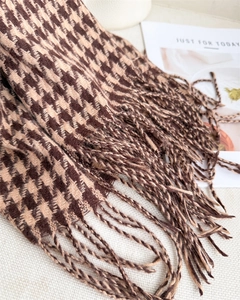 Close-up of houndstooth scarf texture with long fringe tassels in brown and beige