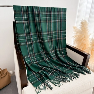 Detail of dark green plaid scarf with fringe texture on a minimalist armchair