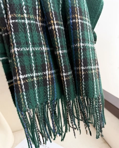 Detailed view of green plaid scarf texture and fringe accents in cashmere-like knit