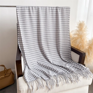 Detail of grey houndstooth scarf featuring long fringe tassels and soft cashmere texture