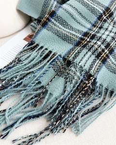 Close-up of teal geometric jacquard pattern with fringe details on a soft autumn shawl