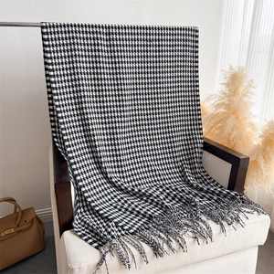 Detailed close-up of a houndscut wool-like scarf with fringe hanging on a metal rack