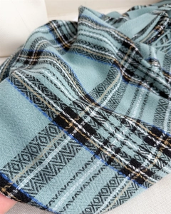 Detail of the woven texture and fringe of a blue Scottish plaid scarf shawl