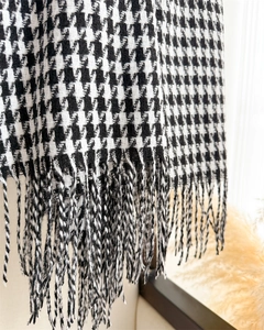 Close-up of black and white houndstooth scarf with elegant long fringe tassels detail