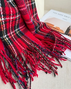 Detail of red plaid scarf fringe and soft cashmere-like texture with classic British pattern