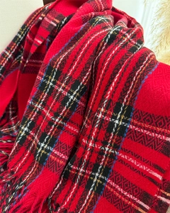 Detail of red plaid cashmere-like scarf showing soft woven texture and fringe trim