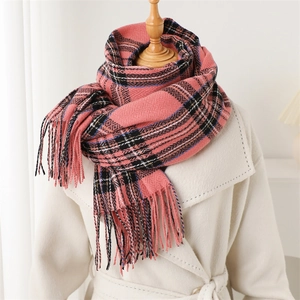 Classic pink plaid cashmere scarf with long tassels worn over a beige winter coat