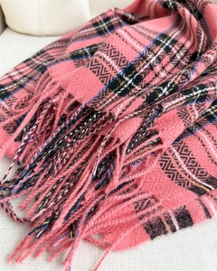 Close-up of pink plaid cashmere-like scarf showing soft herringbone weave and tassel detail