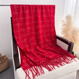 Detailed view of red plaid scarf with long fringes and soft cashmere-like texture