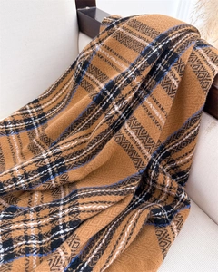 Close-up of caramel plaid scarf showing detailed geometric knit texture and tassels