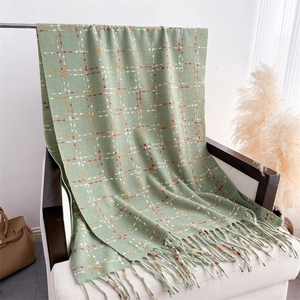 Close-up of green plaid cashmere scarf with long fringe on a white sofa chair