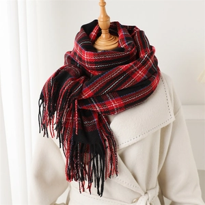 Detailed view of red and black plaid scarf with fringe paired with white coat