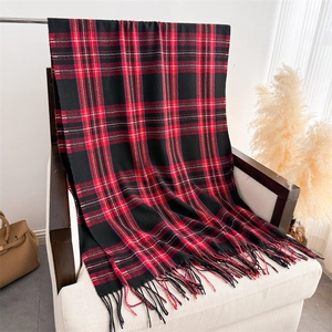 Detail view of plaid cashmere scarf with soft fringes hanging on a wooden chair