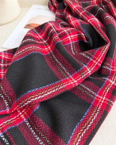 Detailed macro view of the thick red and black plaid knit scarf with golden pattern