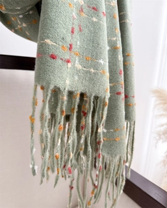 Detailed view of soft light green plaid scarf with fringe and cozy knitted wool texture