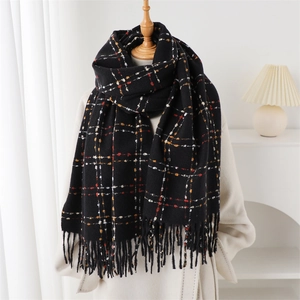 Detail of black plaid cashmere scarf featuring soft knit texture and long tassel edges