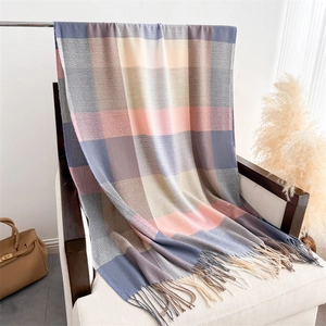 Close-up of pastel plaid scarf with tassels draped on a chair for autumn winter style