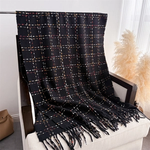 Close-up of winter knit scarf with colorful check patterns and long fringe details