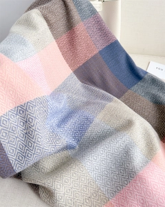 Detailed close-up of soft plaid texture in pastel pink, blue and grey cashmere-like fabric