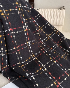 Detail shot of black cashmere-like scarf with colorful plaid pattern on a chair