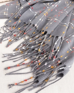 Close-up of grey knit scarf texture with colorful fiber dots and elegant fringe details