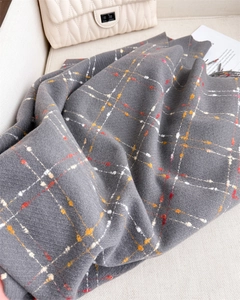 Detailed close-up of dark grey checked pashmina scarf with soft knit texture and fringe