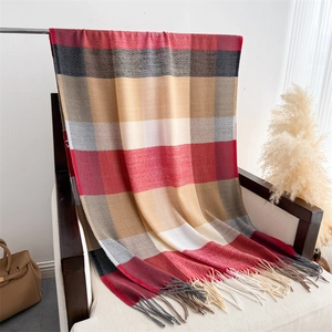 Detail of plaid scarf with tassels in red and grey draped on a wooden chair