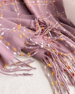 Close-up of mauve plaid scarf with orange accents and soft fringed tassel details