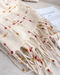 Detail of beige cashmere-feel scarf featuring colorful flocked polka dots and fringe
