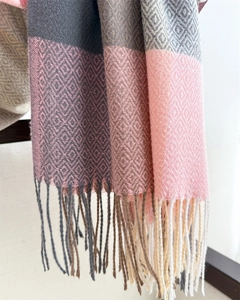 Close-up of geometric knit patterns and tassel fringe on a pink plaid scarf