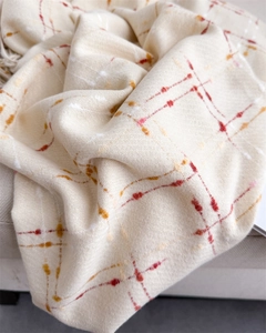 Detailed close-up of cream plaid scarf showing soft cashmere texture and woven patterns