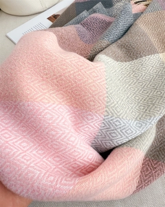 Close-up of geometric plaid pattern on soft cashmere-like knit scarf with tassels