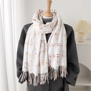 Detail view of white plaid scarf with red and orange dots and soft fringe tassels
