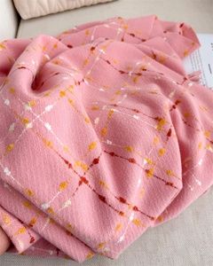 Close-up of pink checkered scarf with soft cashmere texture and artistic yellow dotted lines