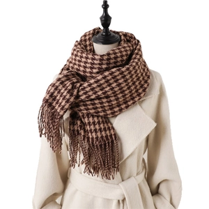 Classic houndstooth winter scarf with fringe tassels worn over a stylish wool coat