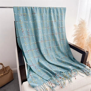 Close-up of light blue checkered scarf with tassels draped on a white wooden chair