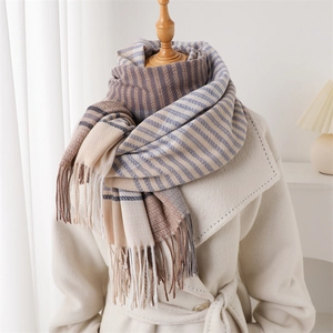 Detail of soft cashmere-like scarf with fringe and elegant beige striped pattern