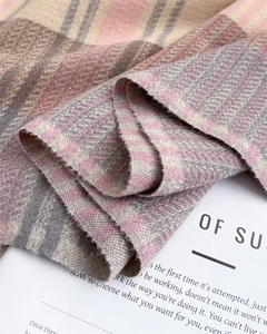 Close-up of soft plaid scarf fabric with pink, beige and grey stripes and fringed edge