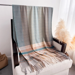 Detail of multi-color striped shawl with soft fringe trim on a white sofa chair