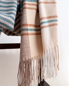 Detail shot of beige plaid scarf with tassels hanging on a wooden chair back