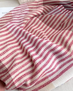 Macro shot of striped knit scarf texture with soft red, beige and grey tassel details