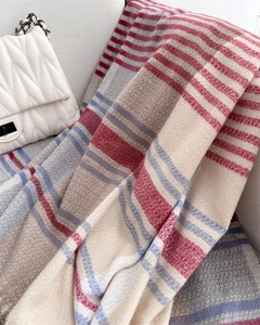 Detail of color-block striped scarf with soft fringe texture on a white sofa