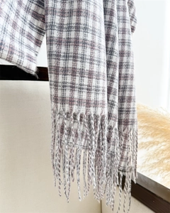 Close-up of black and pink plaid scarf showing fine tassel texture and soft cashmere feel