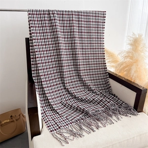 Close-up of soft plaid winter scarf with red and black check patterns and fine tassels