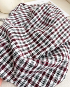 Close-up of red and black plaid scarf texture with soft tassels and woven fringe